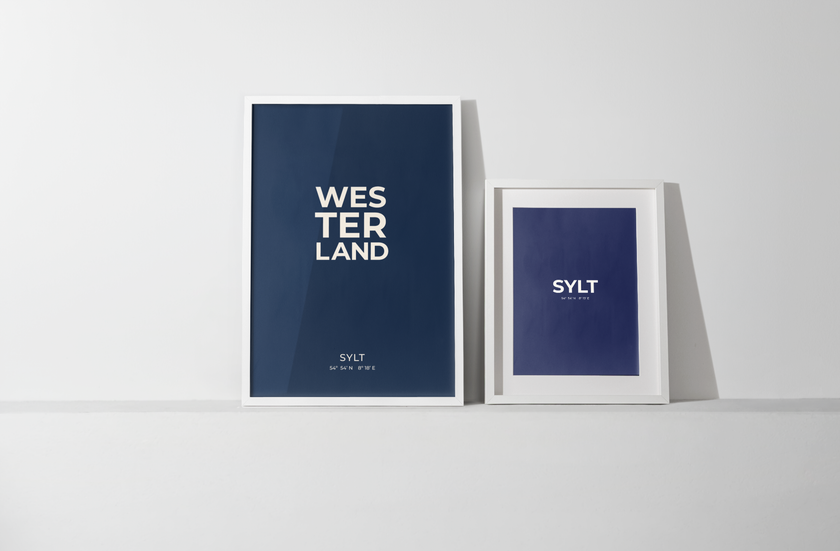 Beide Postergrößen, A3 und 50 x 70 cm, stehen nebeneinander an die Wand gelehnt, um den Größenunterschied der Formate und die gemeinsame Wirkung zu zeigen. 